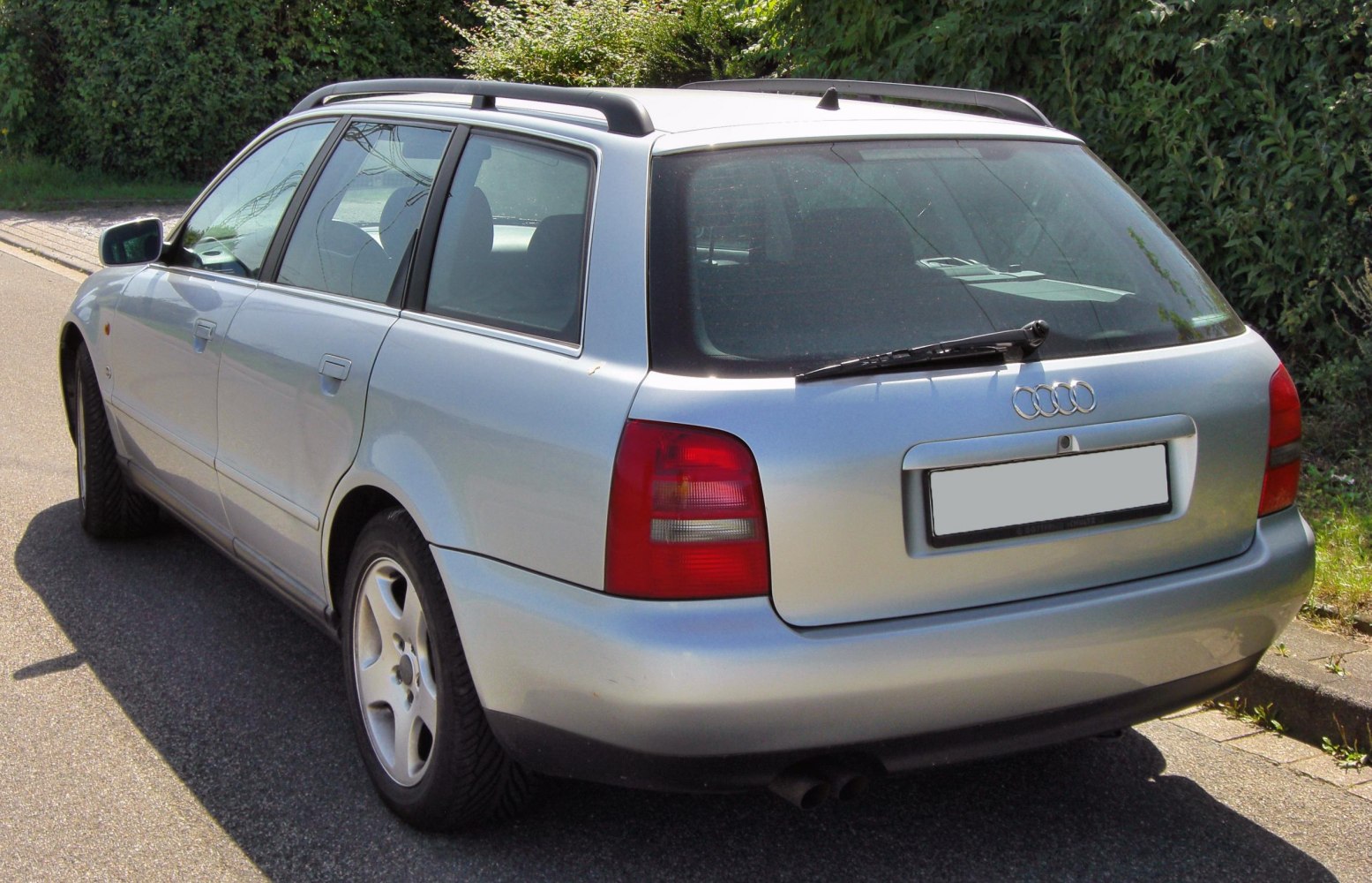 Rear and side view of silver station wagon with roof rails and taillights.