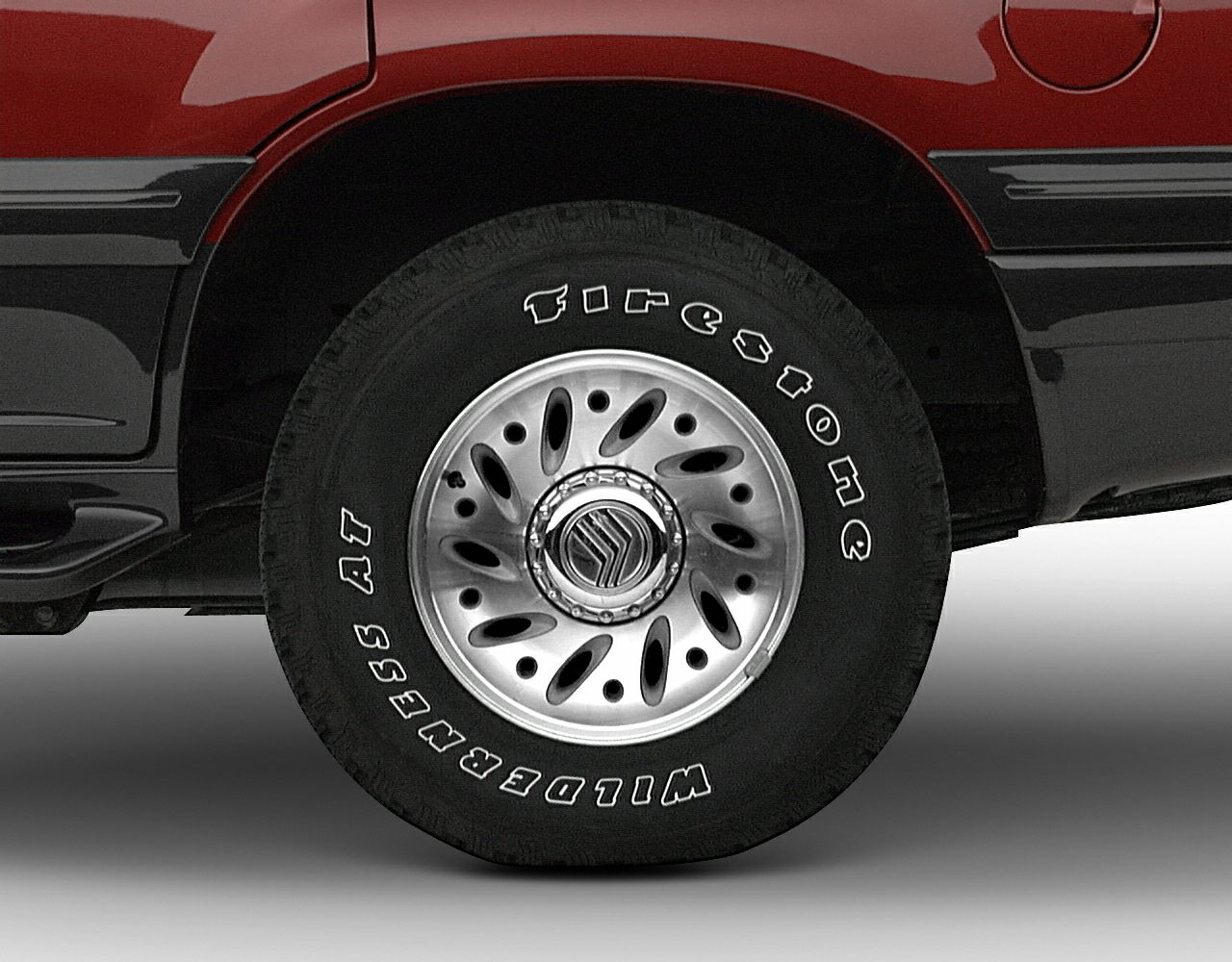Close-up of alloy rim with Firestone Wilderness AT tire on vehicle rear wheel arch