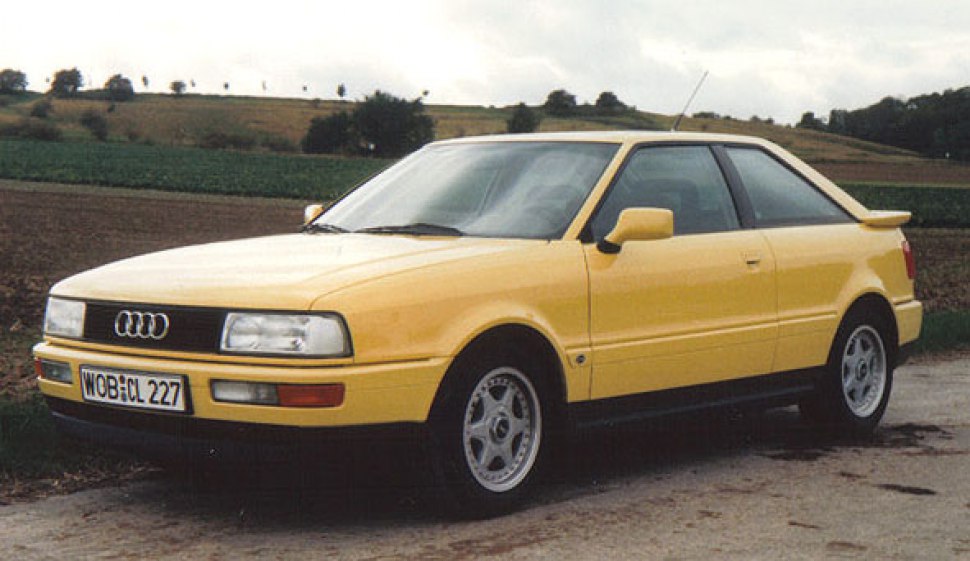 Yellow coupe with rectangular headlights, rear spoiler, and alloy wheels