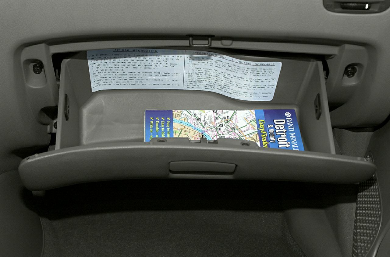 Open glove compartment with visible map and airbag information label