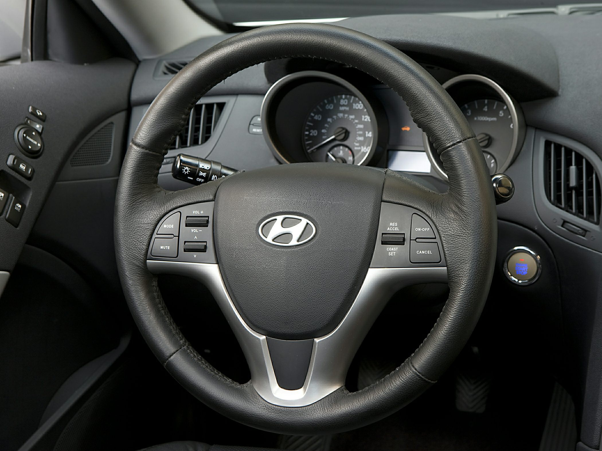 Steering wheel with audio and cruise control buttons, dashboard gauges, push start button