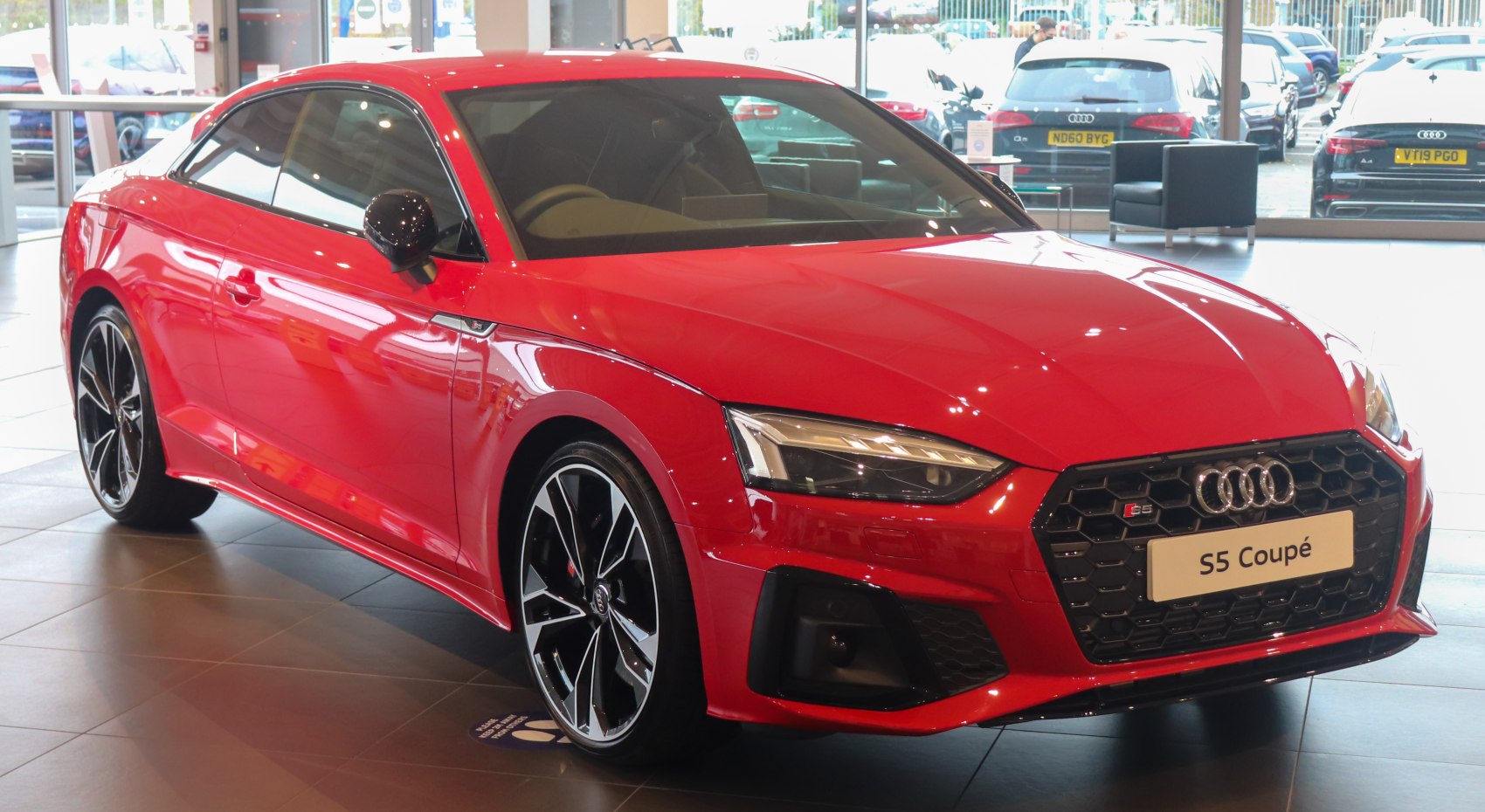 Red coupe with aggressive headlights and honeycomb grille