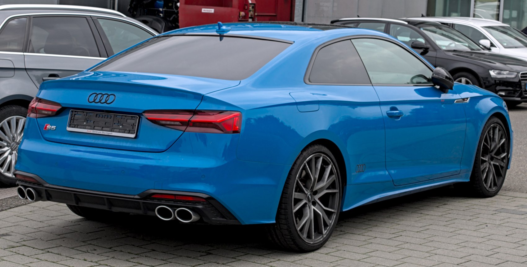 Rear and side view of a blue coupe with quad exhausts and dark alloy wheels