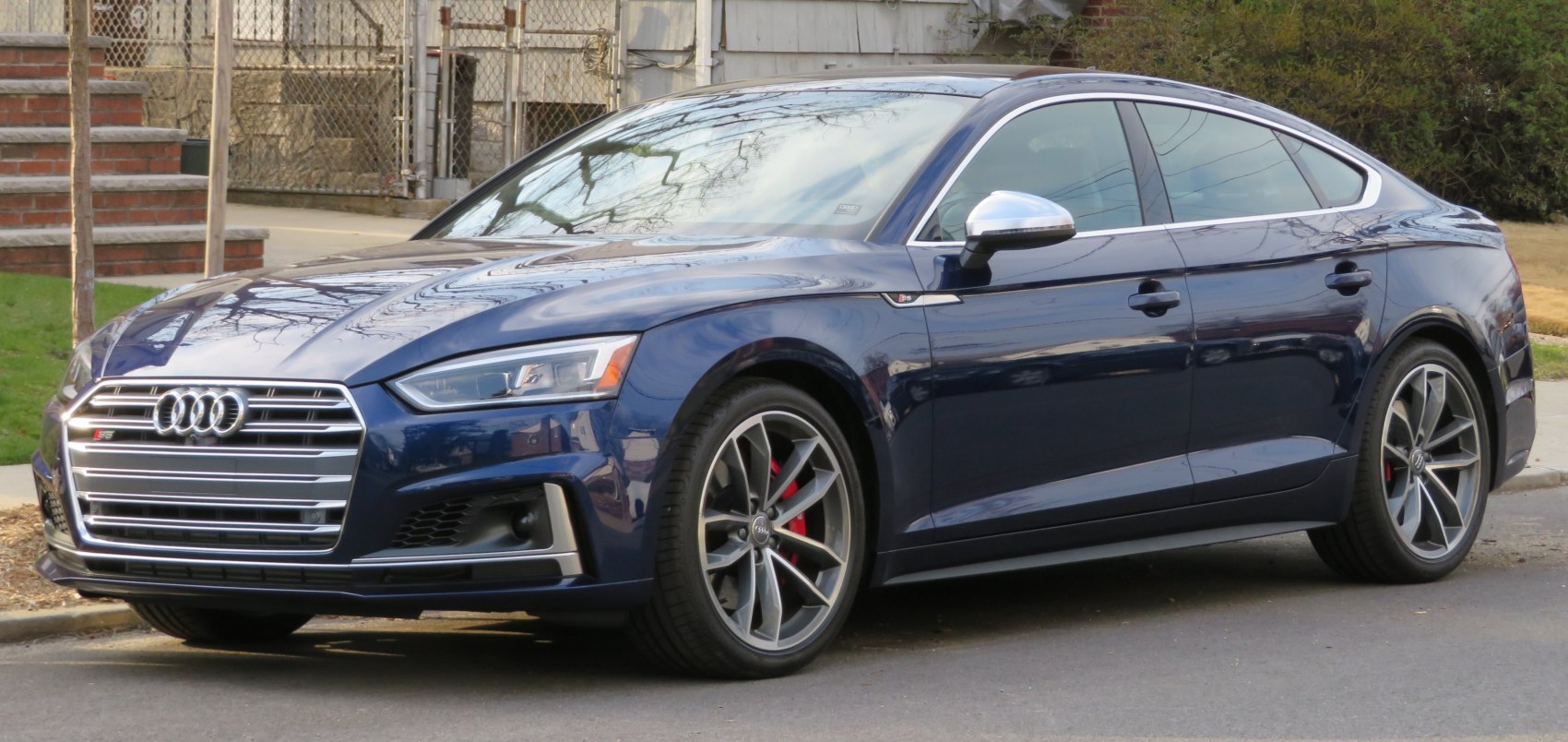 Front side view of a blue sporty sedan with prominent grille and alloy wheels
