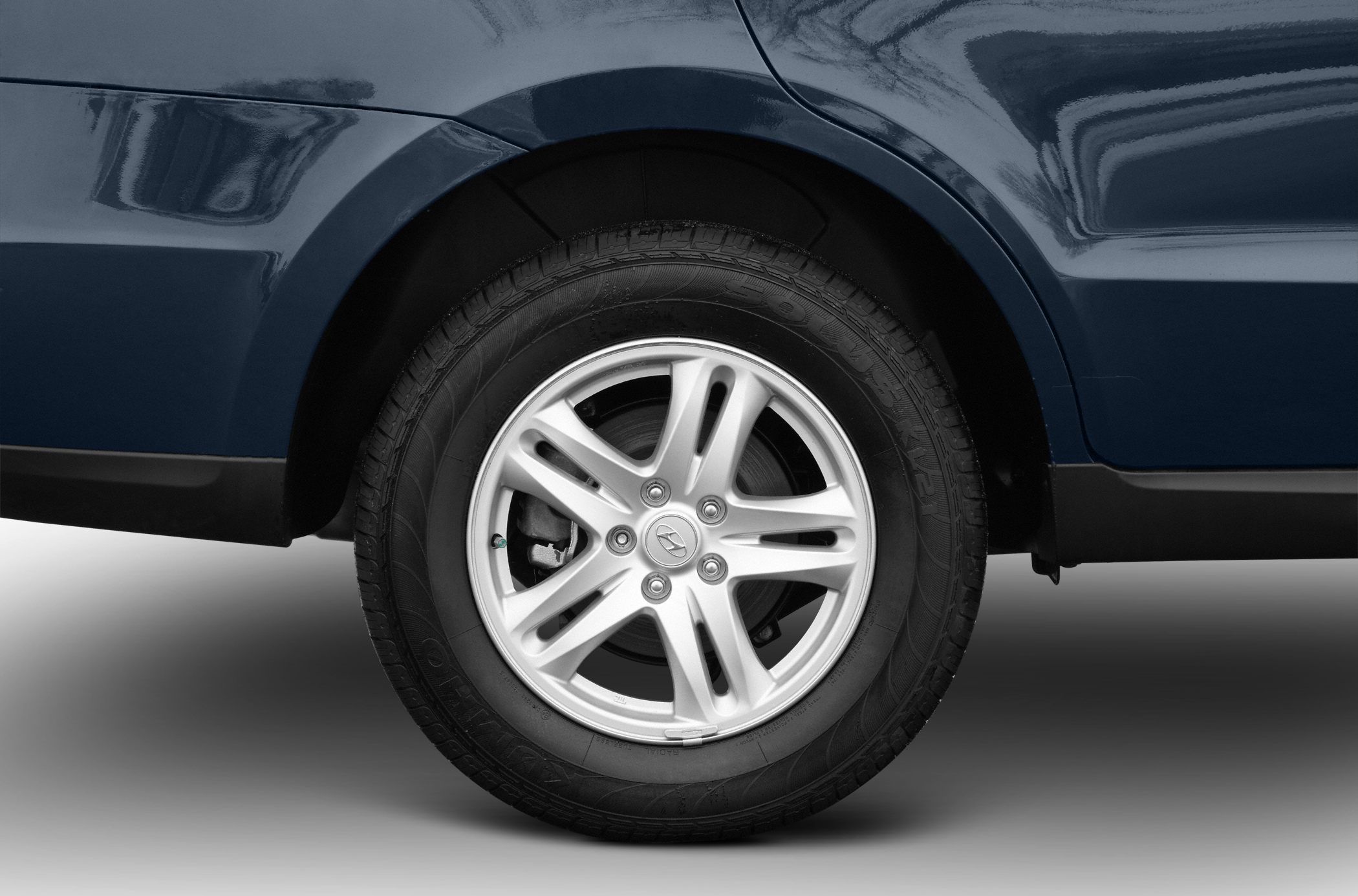 Alloy wheel and tire close-up on dark blue vehicle