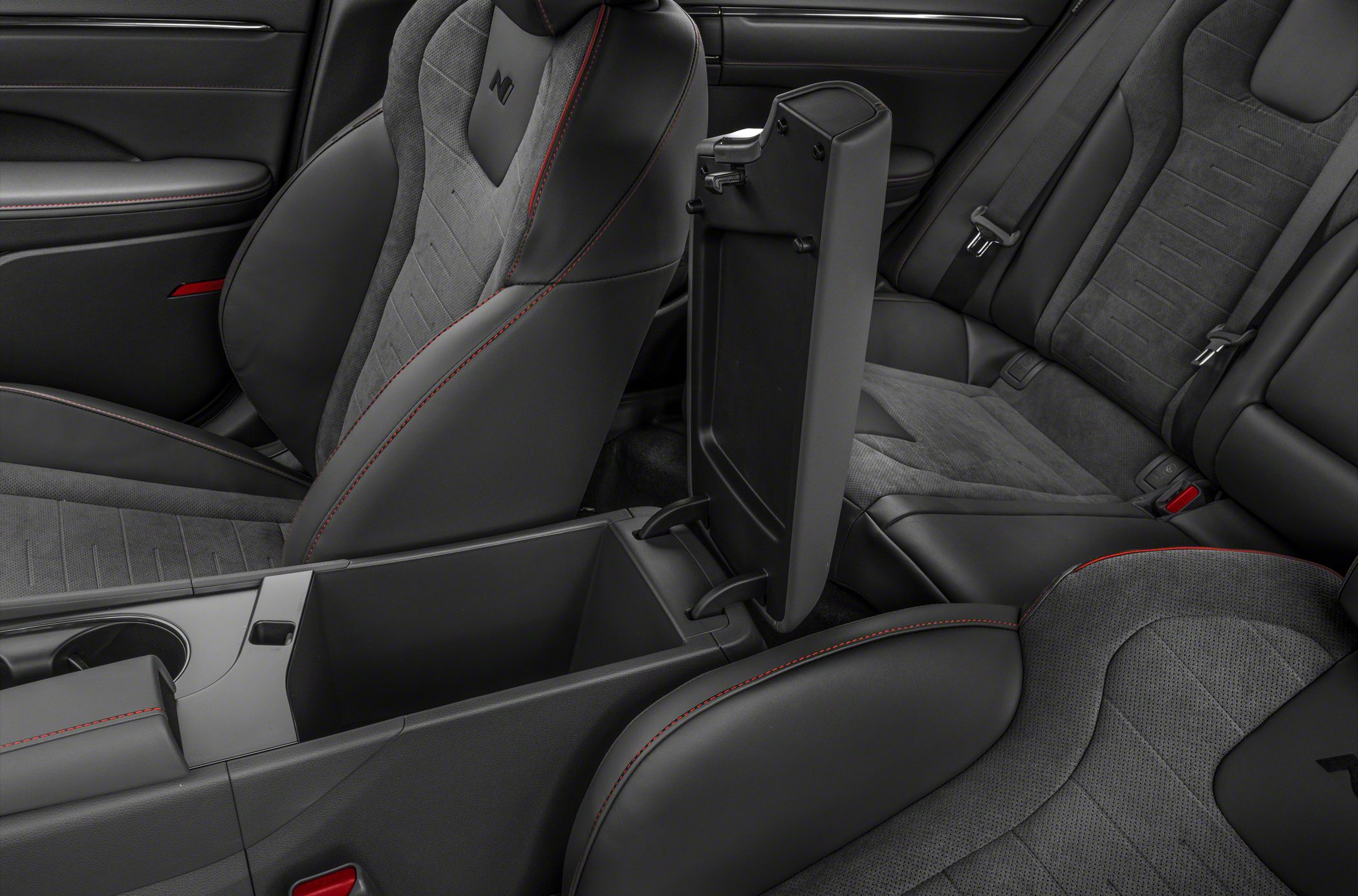 Sporty car seats with red stitching and open center console storage.