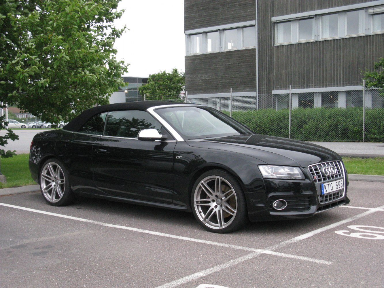 Black convertible with alloy wheels and soft top roof in side profile