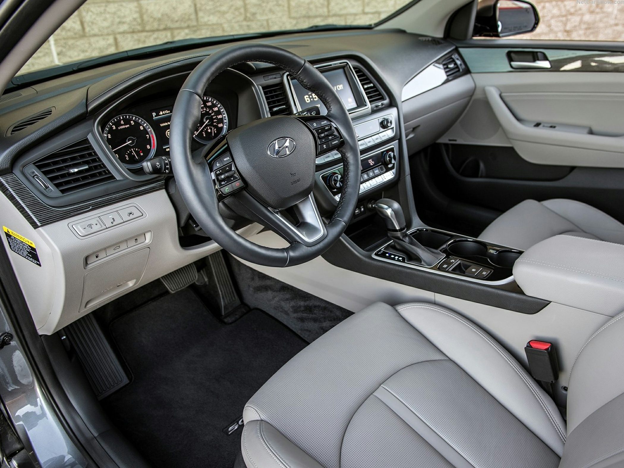 Modern car interior with dashboard, steering wheel controls, and leather seats.