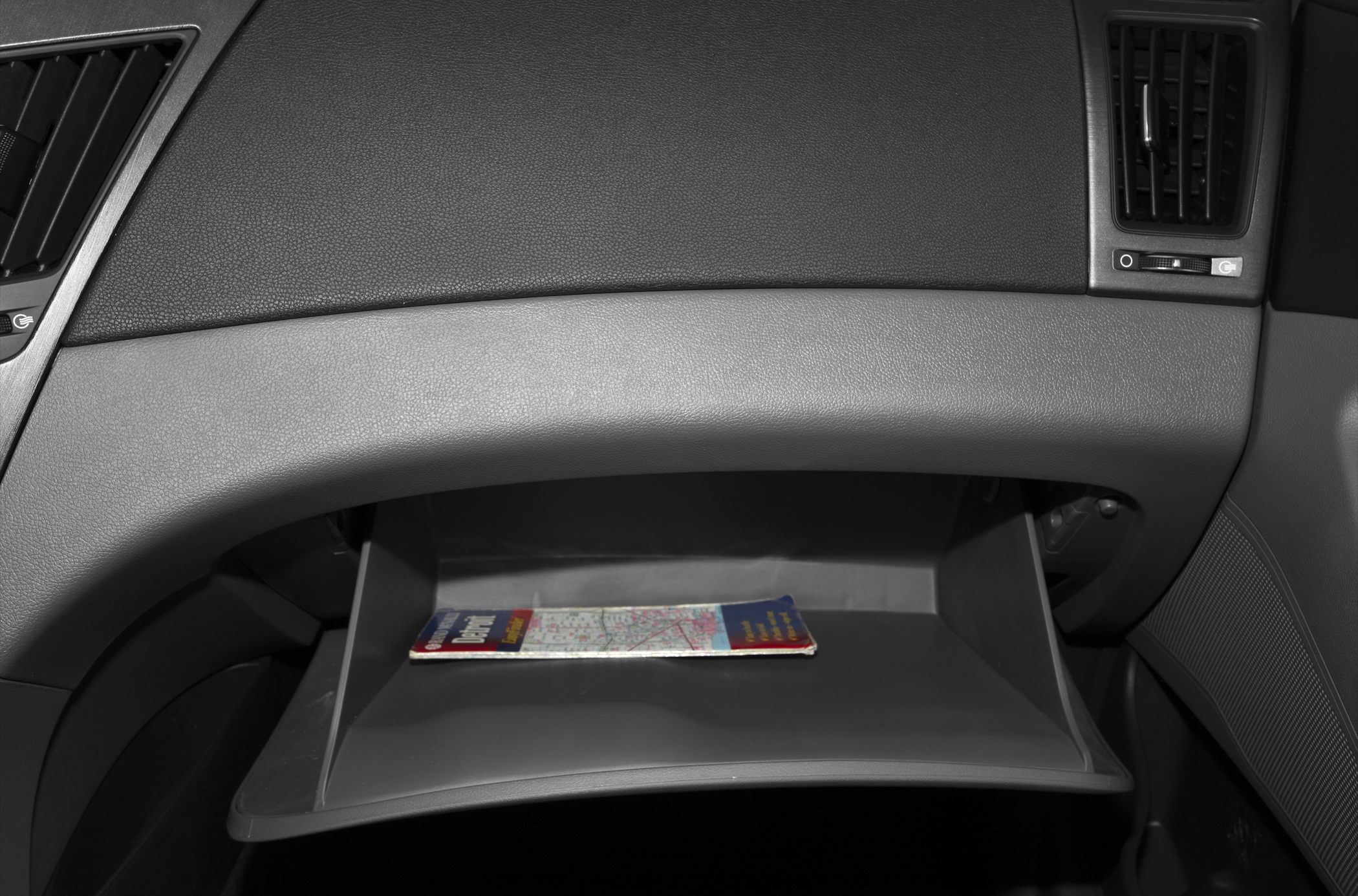 Open glove compartment with map inside in car interior