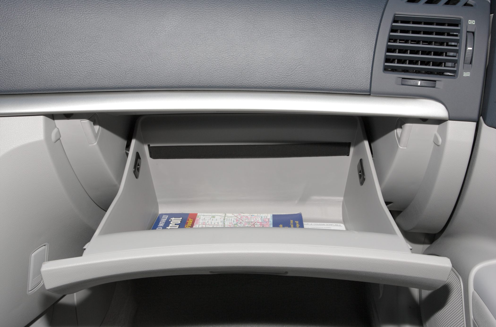 Open glove compartment with car map inside and dashboard air vent