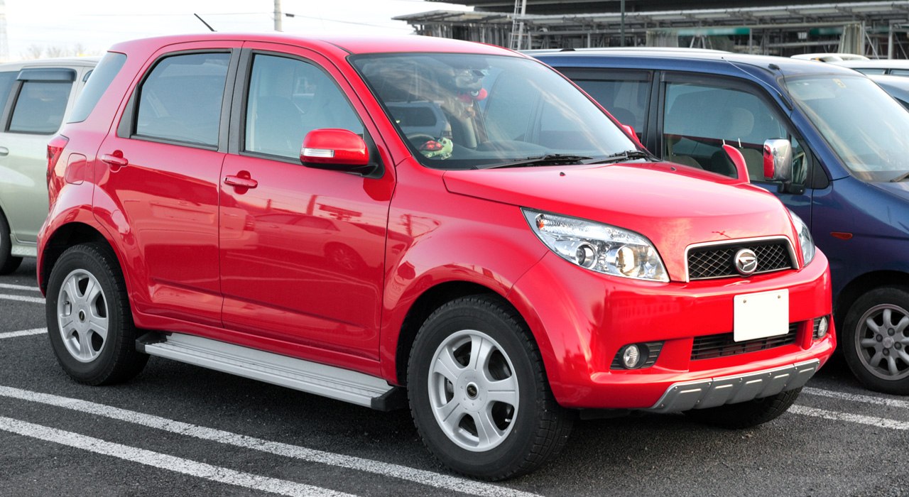 Red compact SUV with side step and alloy wheels from front-side angle
