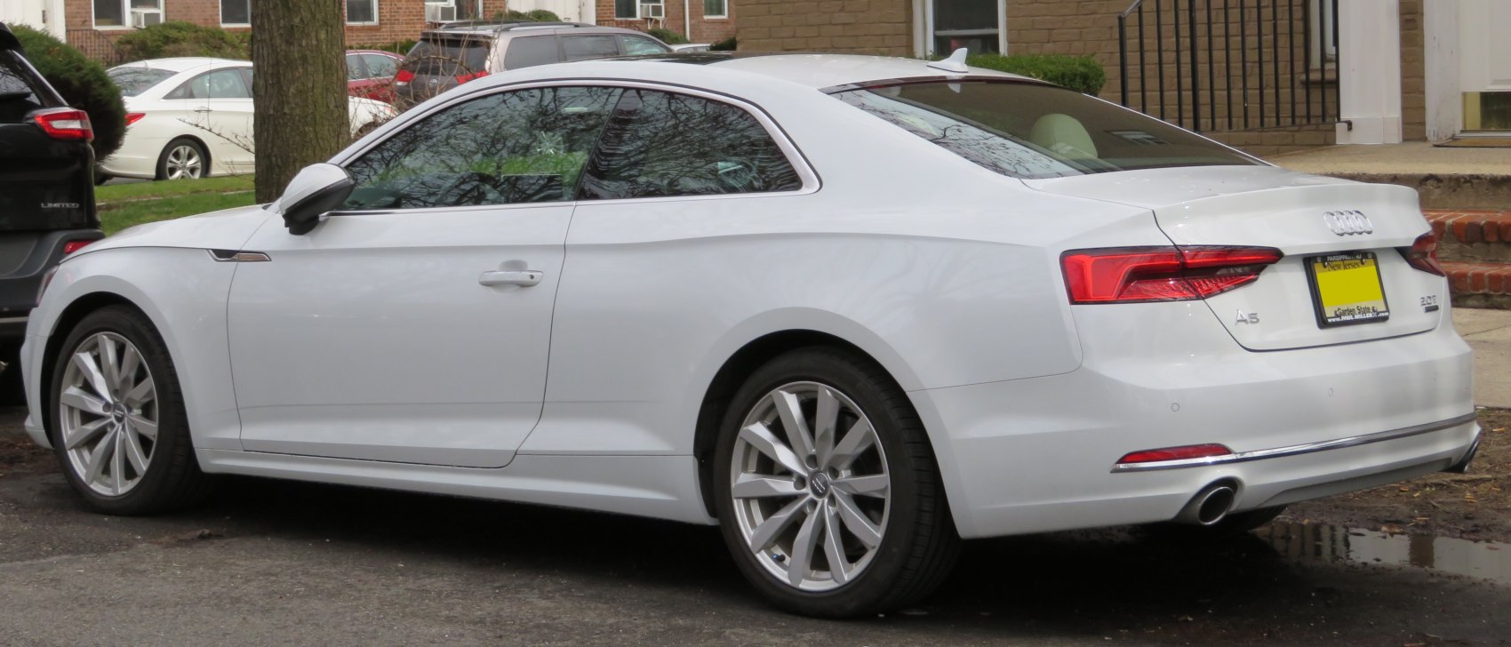 Rear and side profile of sleek white coupe with distinctive tail lights.