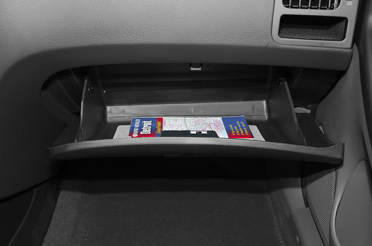 Open glove compartment with a map inside in a vehicle interior.