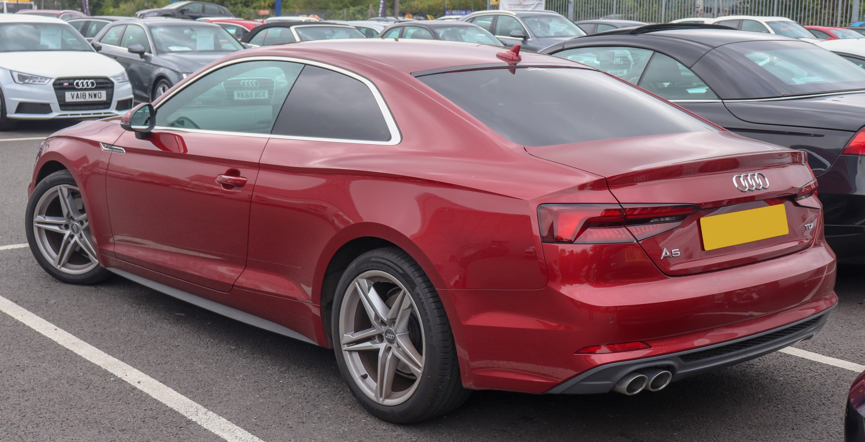 Rear side view of red coupe with dual exhausts and alloy wheels