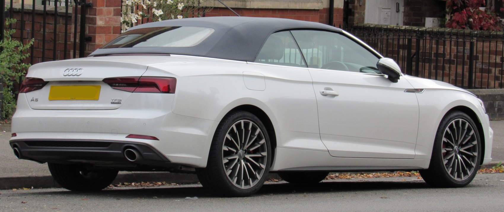 Rear view of convertible with soft top, dual exhausts, and multi-spoke alloy wheels