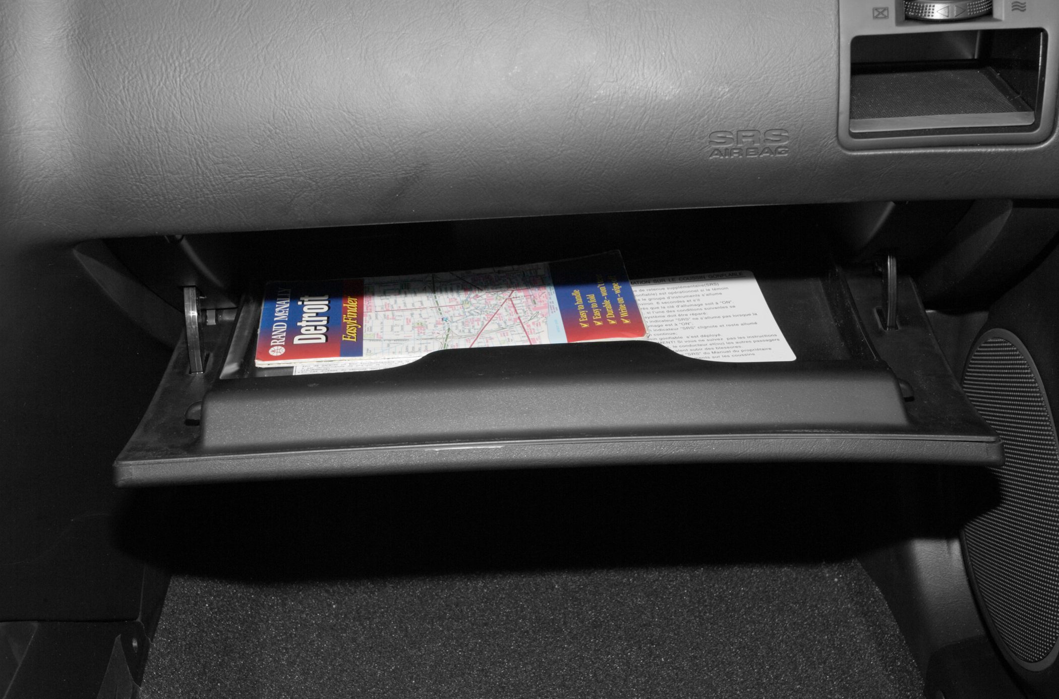 Open glove box with map and instructions inside