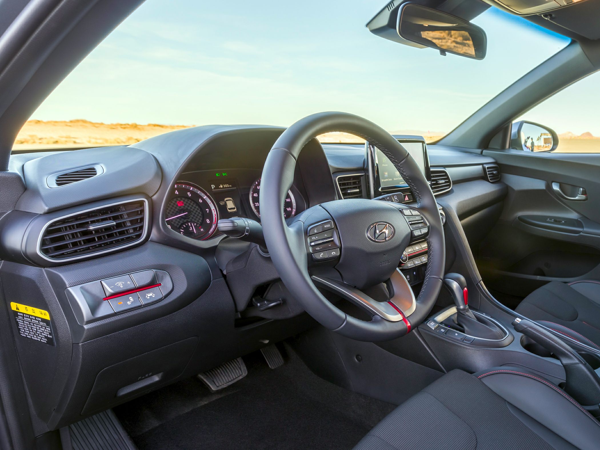 Car interior dashboard, steering wheel with controls, and center console gear shift