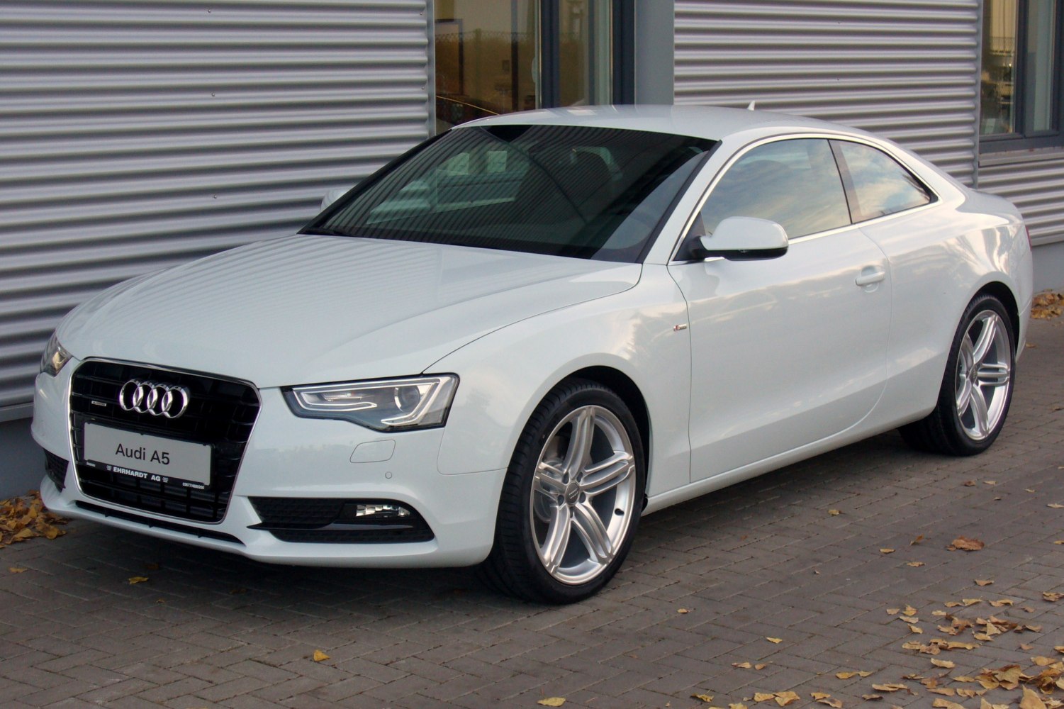 Front side view of white coupe with LED headlights and sporty alloy wheels.