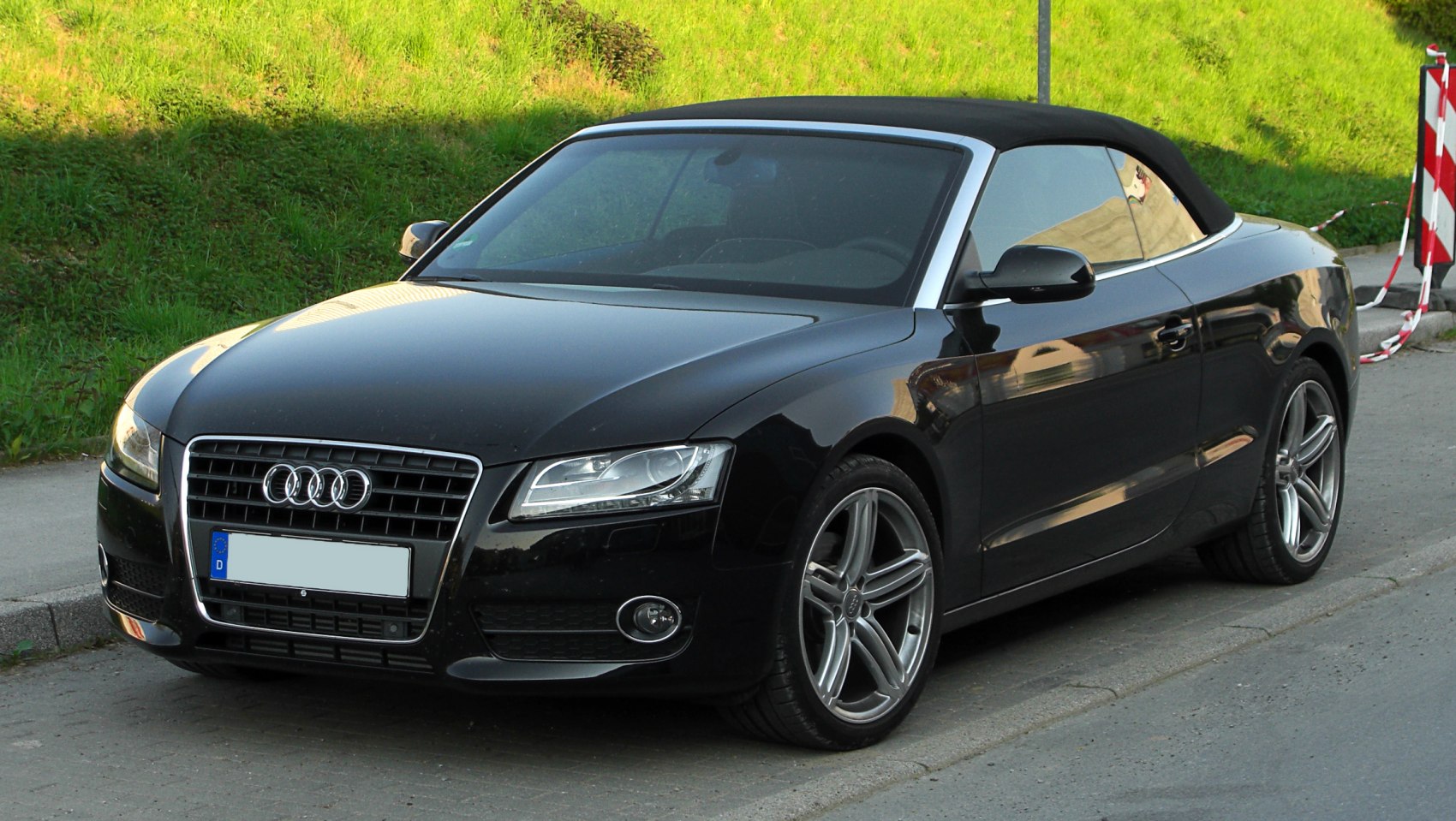 Front-side view of black convertible with soft top and sporty wheels