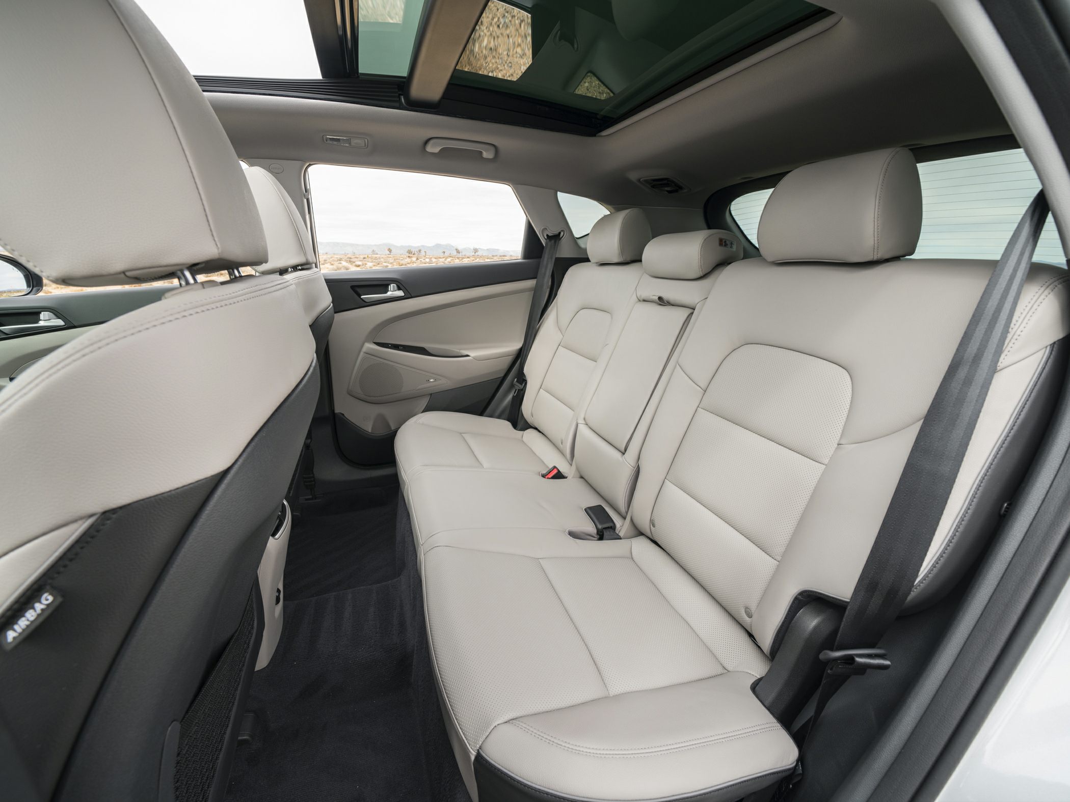 Beige leather rear seats with panoramic sunroof in a spacious SUV interior