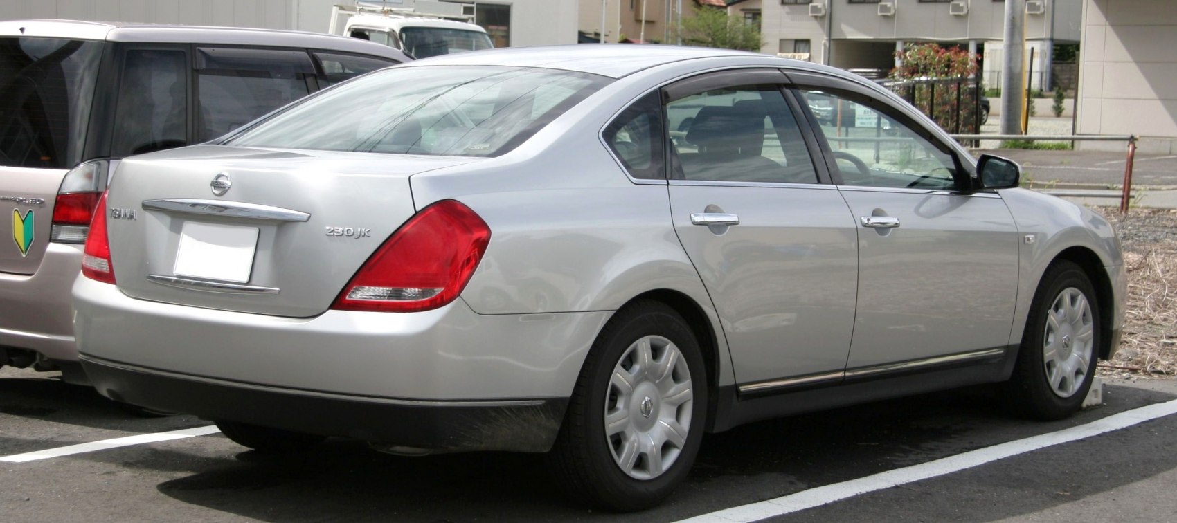 Rear side view of mid-size sedan with red tail lights and smooth silver body