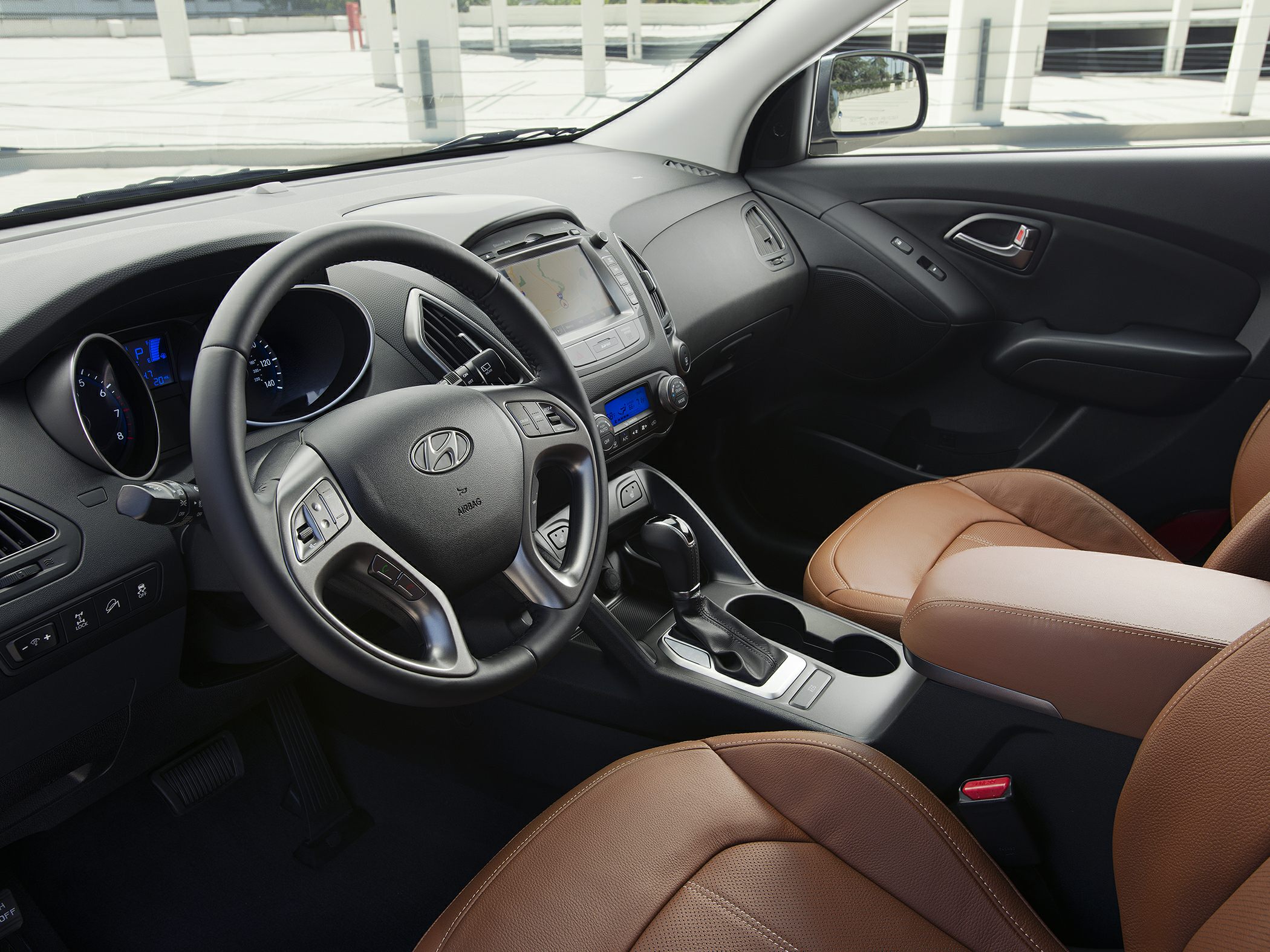 Steering wheel, dashboard with infotainment, and brown leather seats