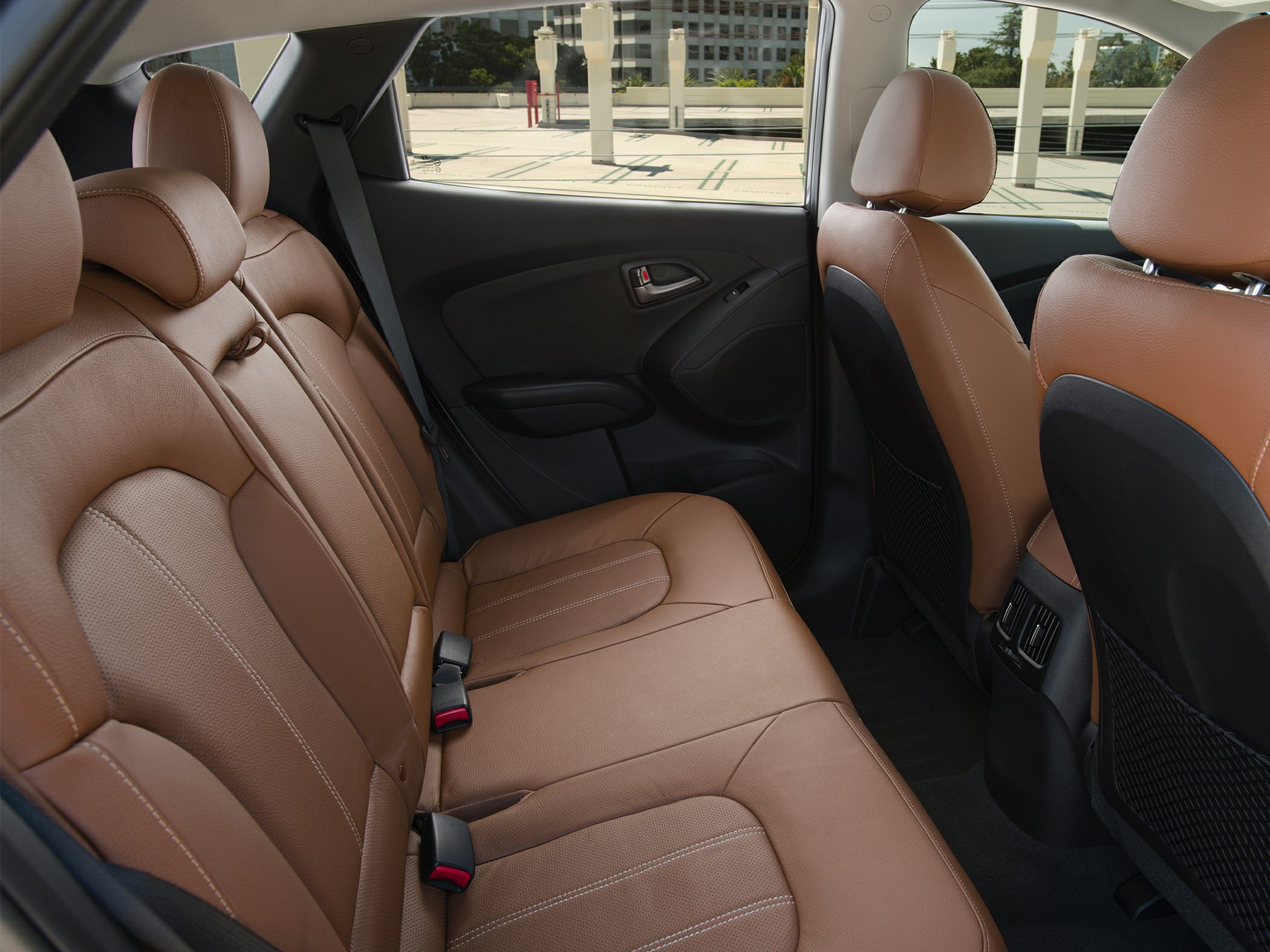Spacious rear seat with brown leather upholstery and rear air vents.
