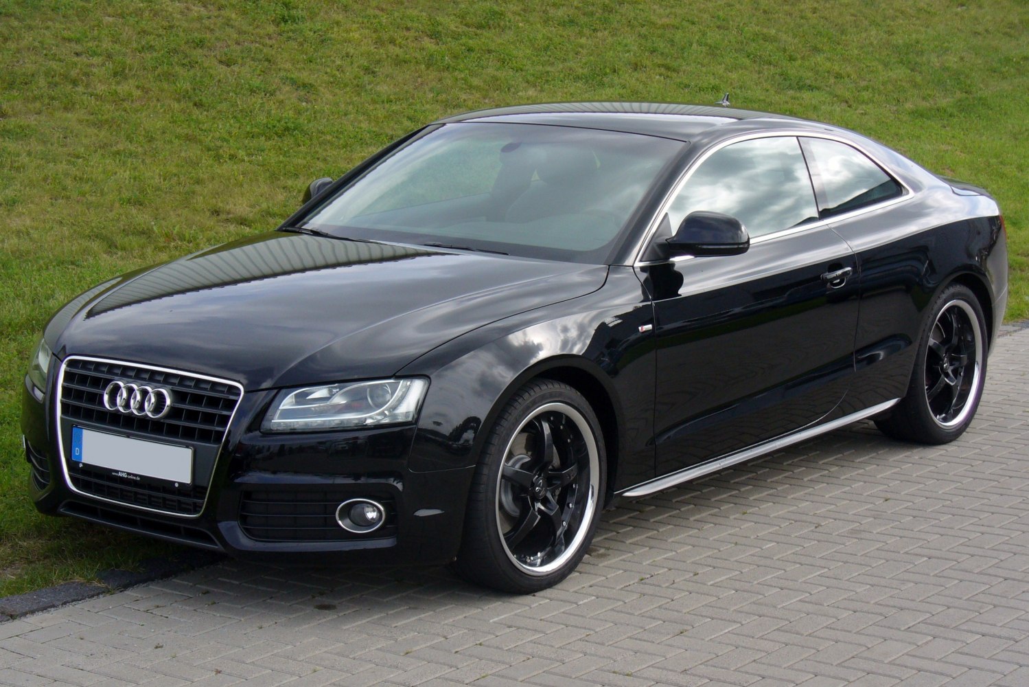 Black sporty coupe front view with distinctive alloy wheels