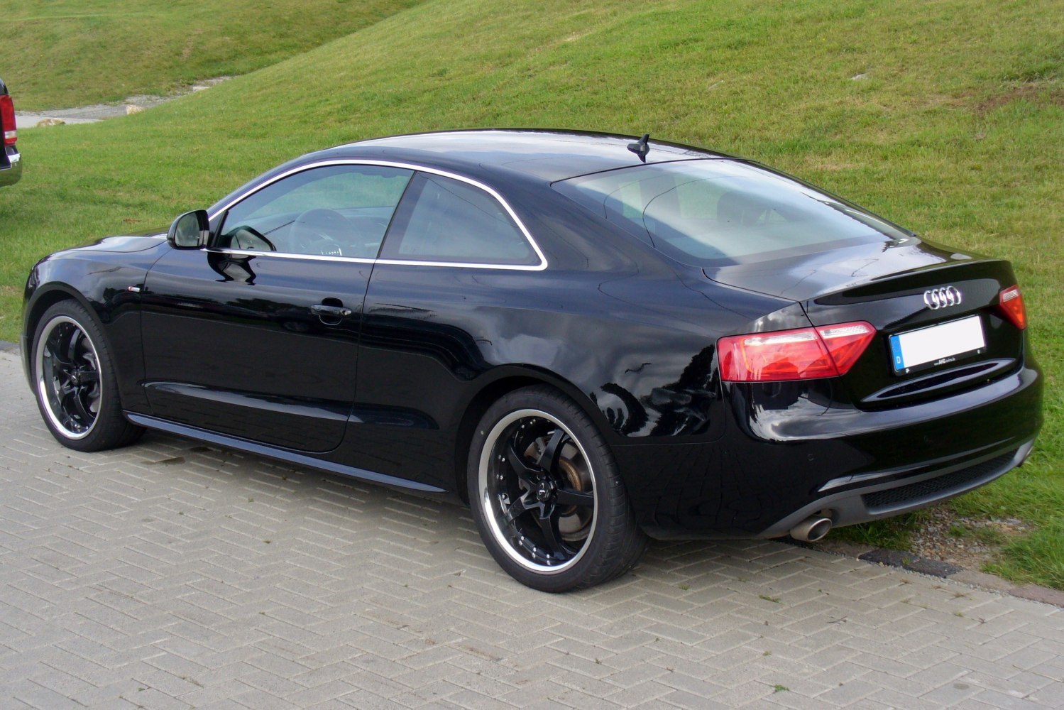 Black coupe with black alloy wheels and rear spoiler