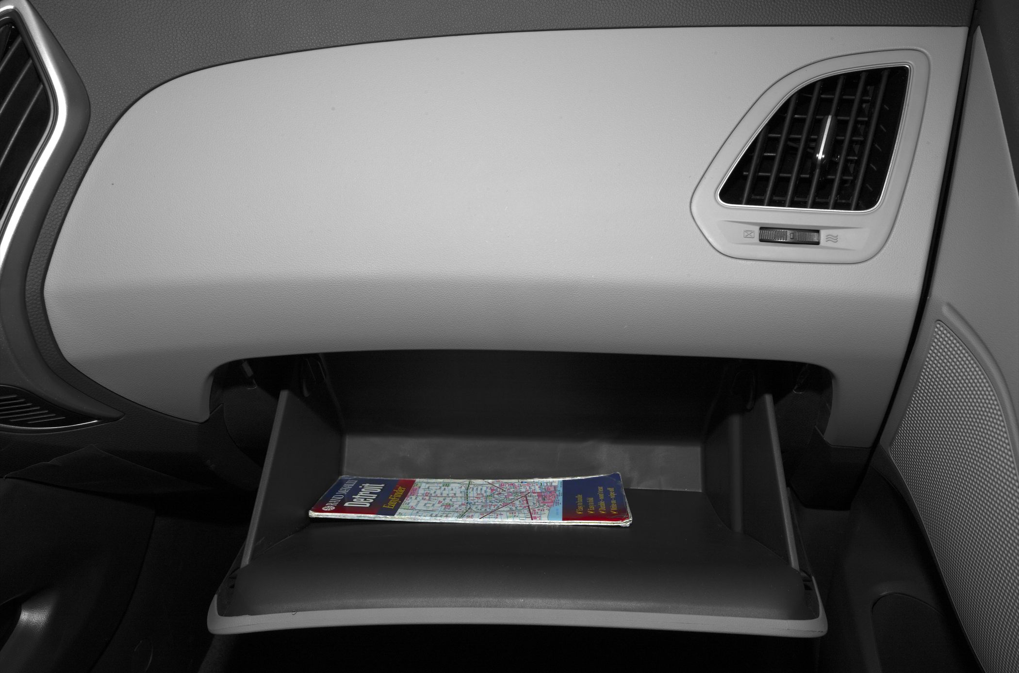 Open glove compartment with map inside on vehicle dashboard