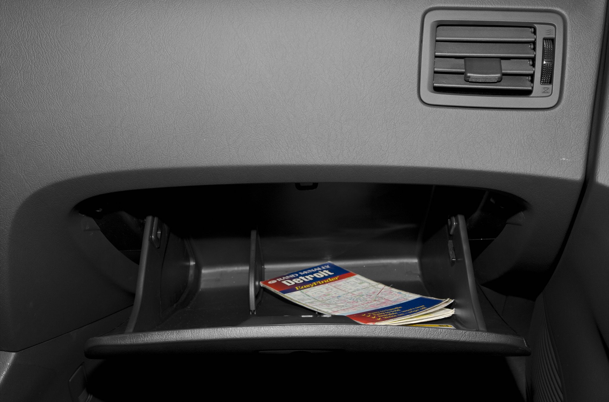 Open glove compartment with a manual inside and air vent above