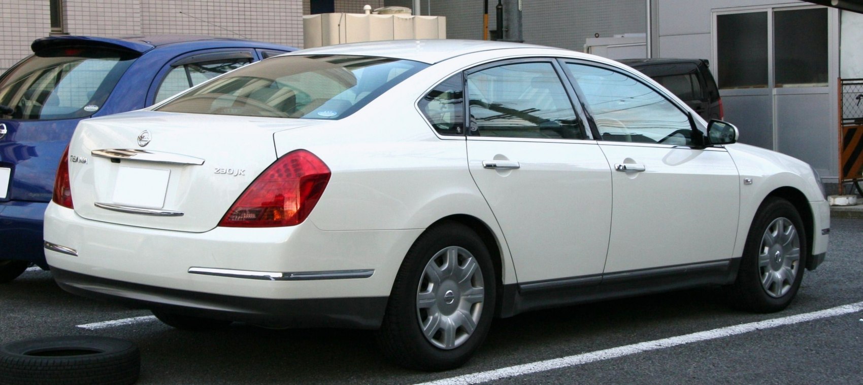Rear and side view of a white sedan with distinct taillights and curved roofline.