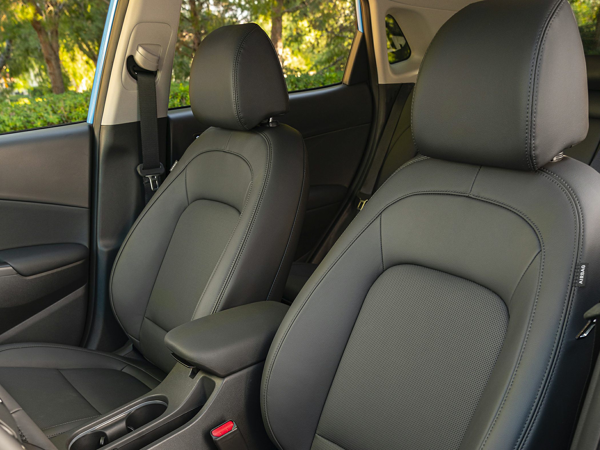 Close-up of front car seats with black leather upholstery and armrest