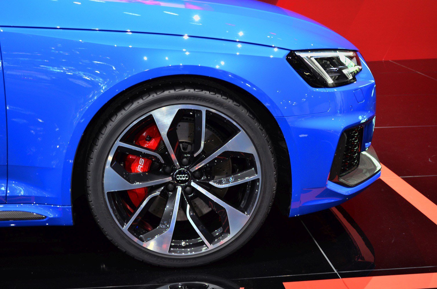 Sporty alloy wheel and LED headlight on blue car front