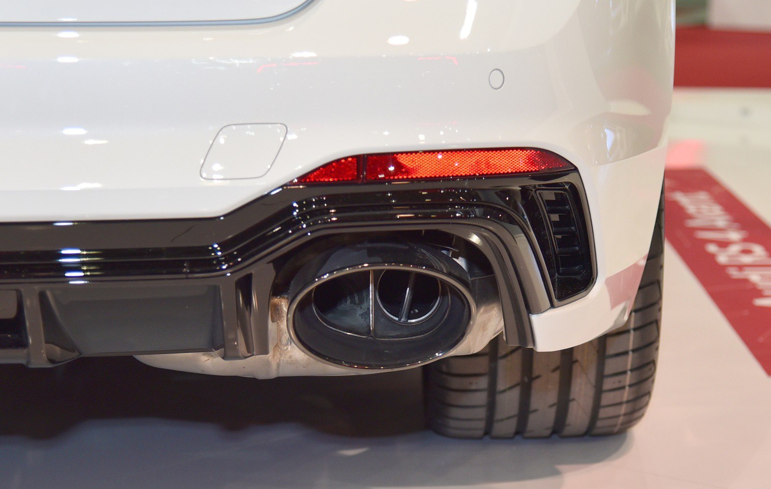 Dual oval rear exhaust and wide performance tire on white rear bumper