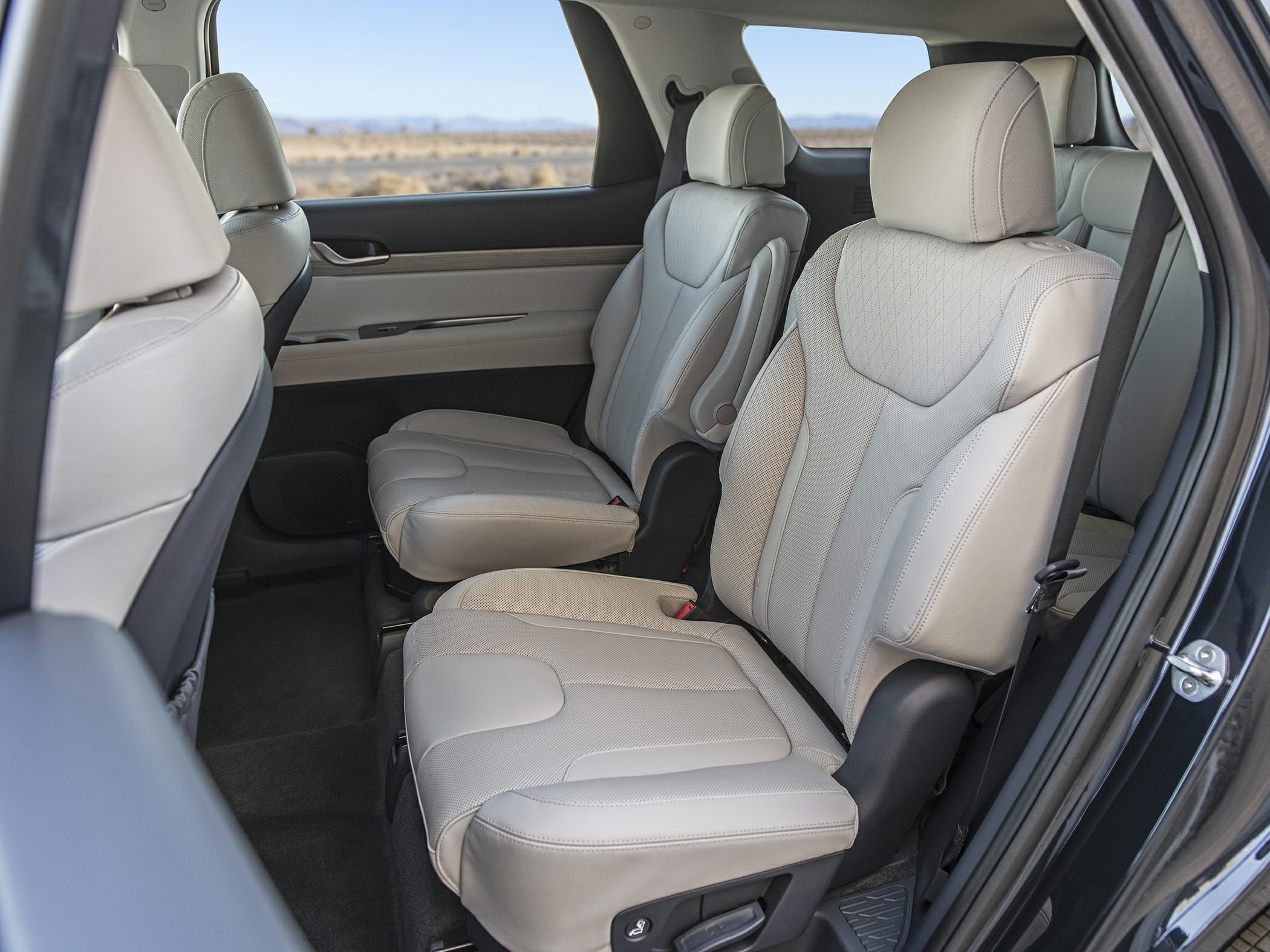 Beige leather mid-row seats with armrests and spacious legroom.