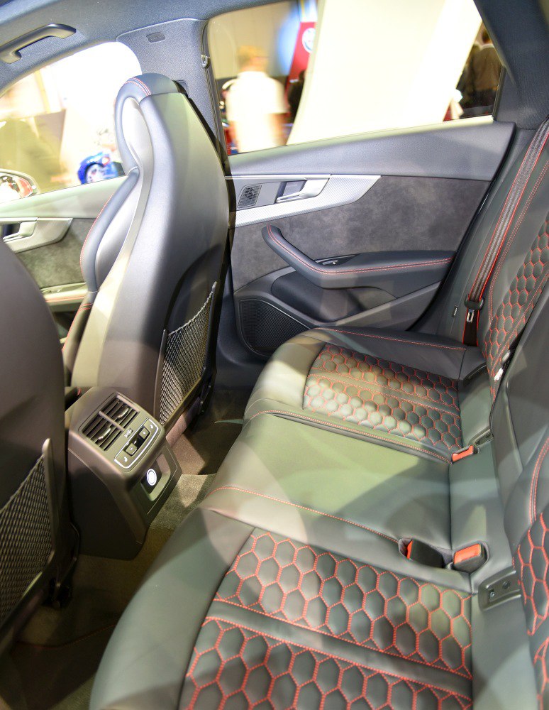 Rear black leather seats with red hexagonal stitching and ventilation controls