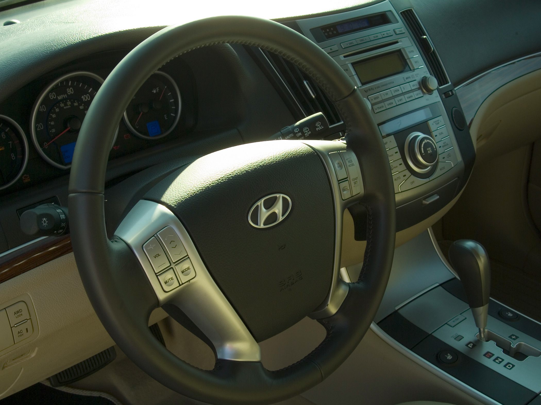 Steering wheel with control buttons and center console with gear shift and dashboard instruments.