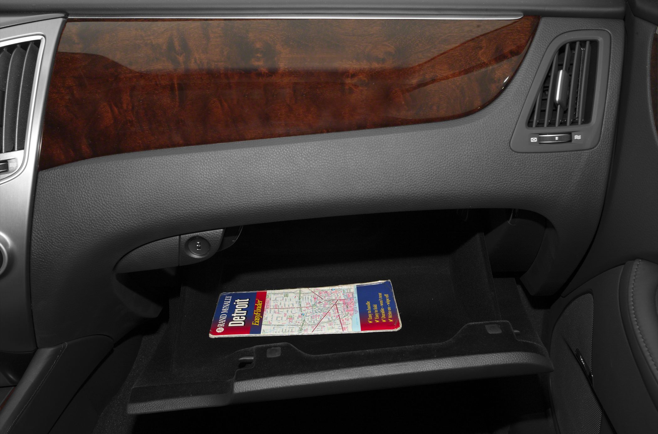 Luxury wood trim dashboard with open glove compartment containing a map