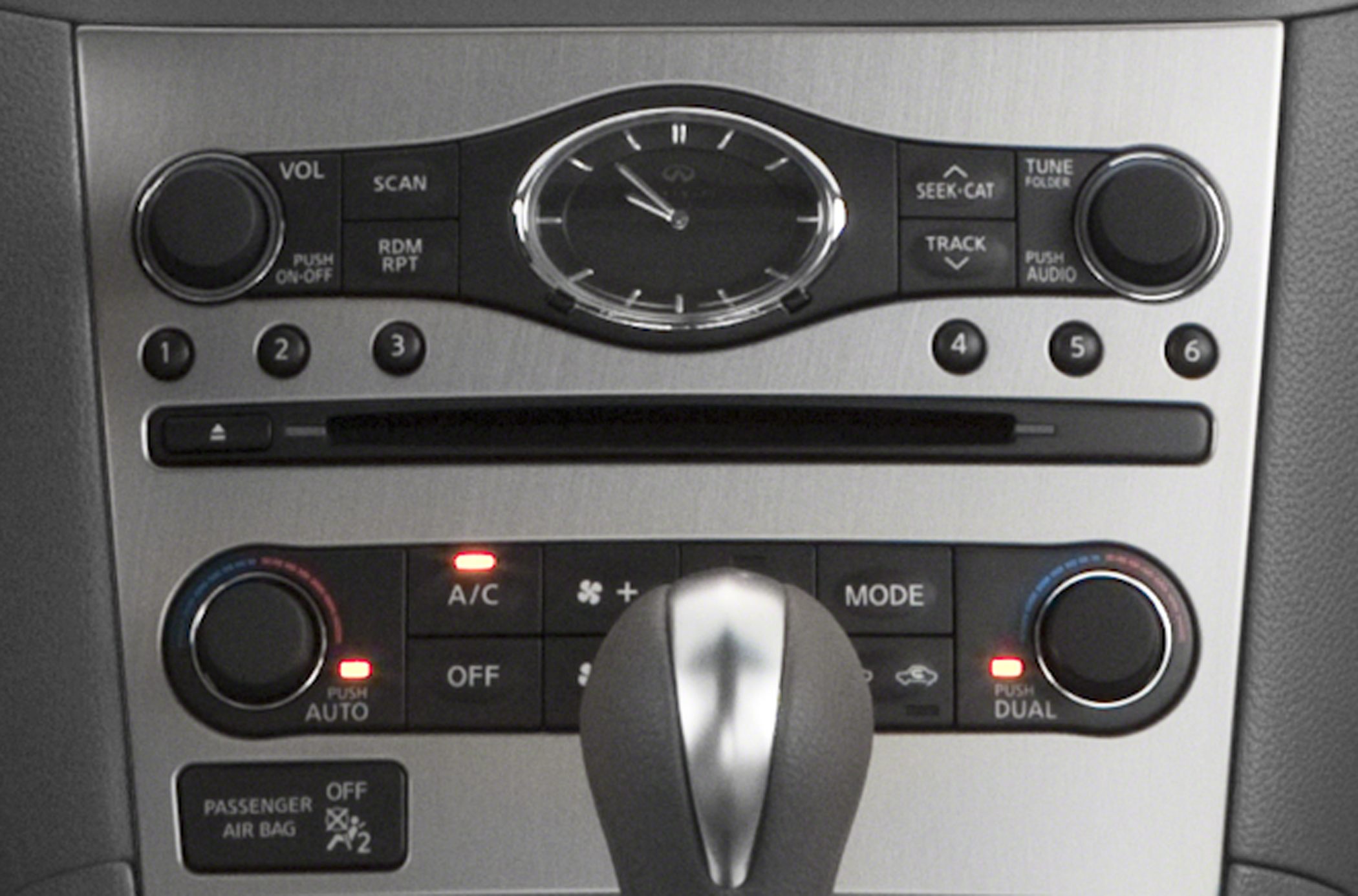 Car interior control panel featuring audio, climate controls, and analog clock