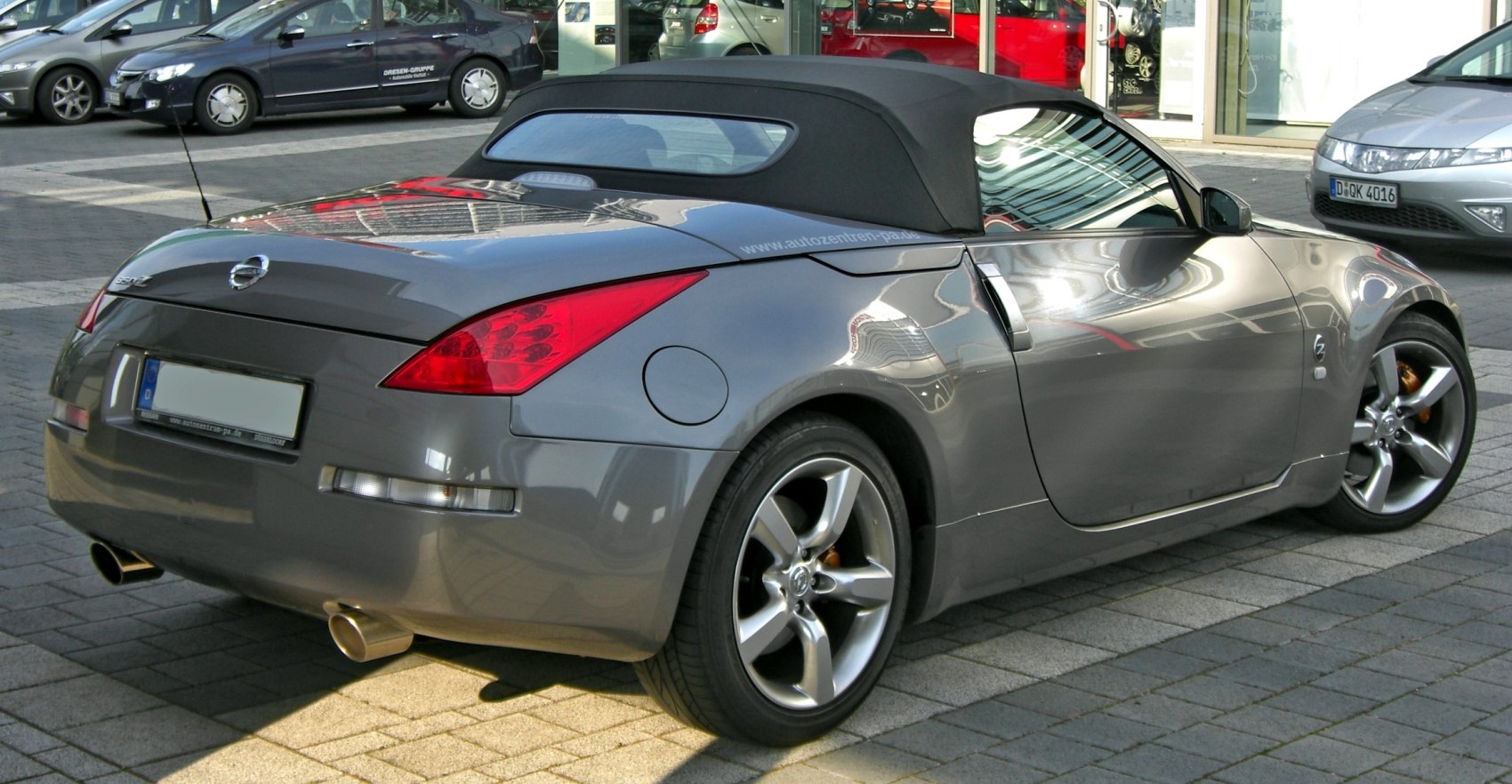 Rear view of a soft top convertible with alloy wheels and dual exhaust.