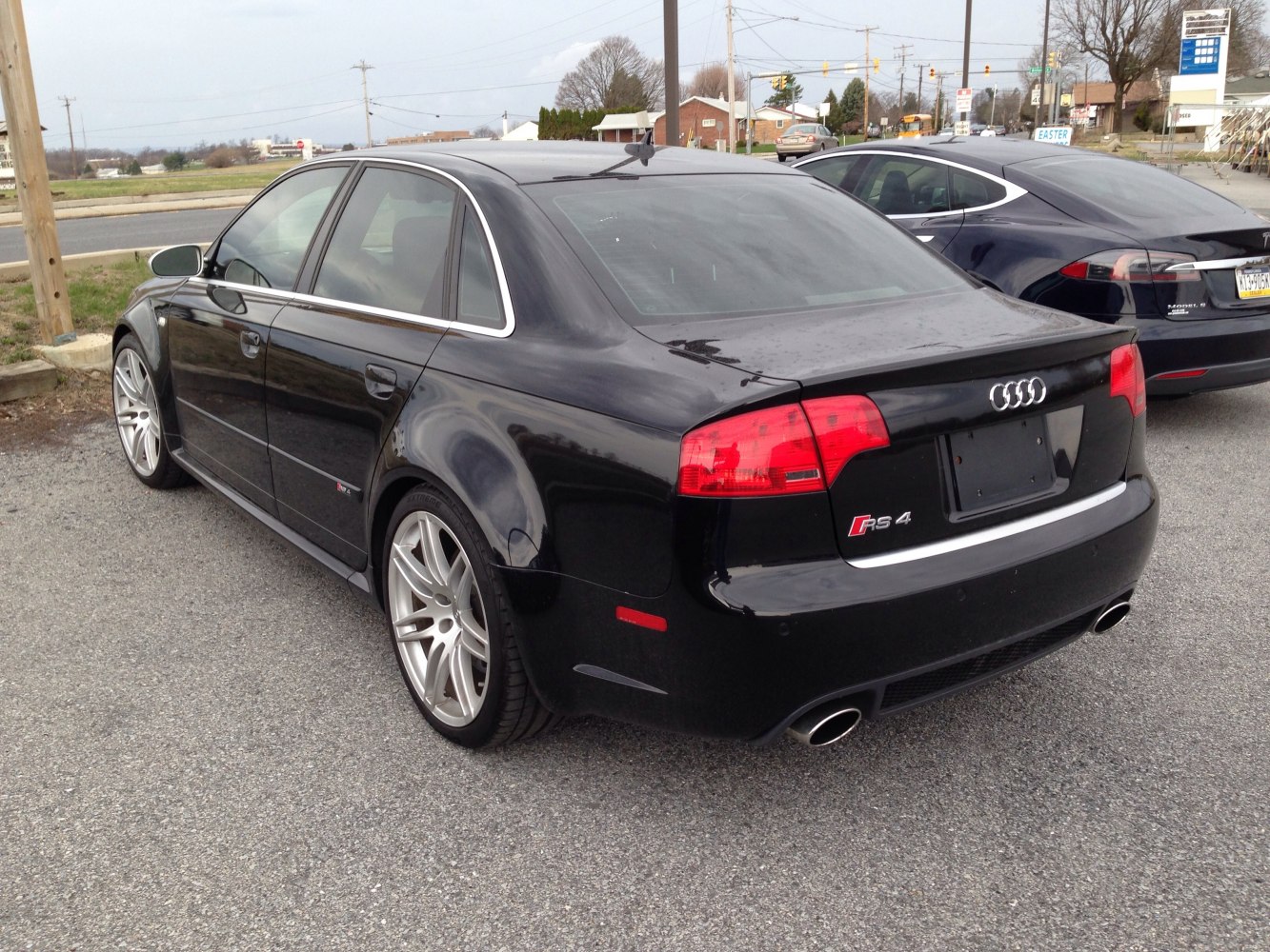 Rear and side view of black sporty saloon with alloy wheels and dual exhausts