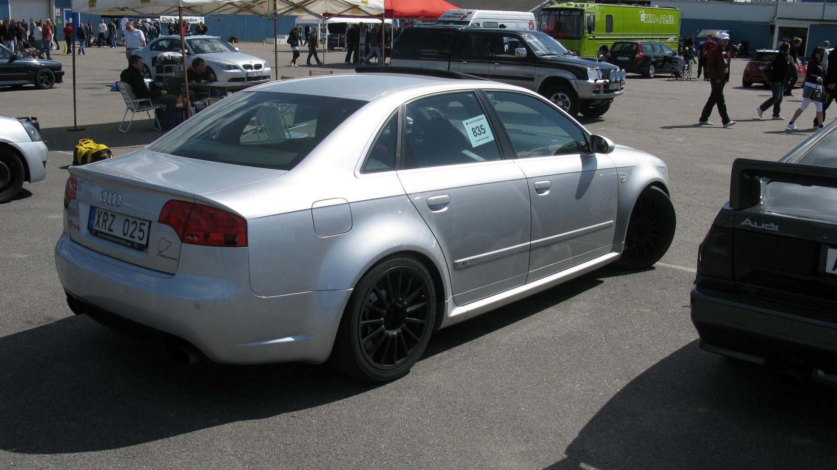 Silver sedan rear side with black alloy wheels at car event