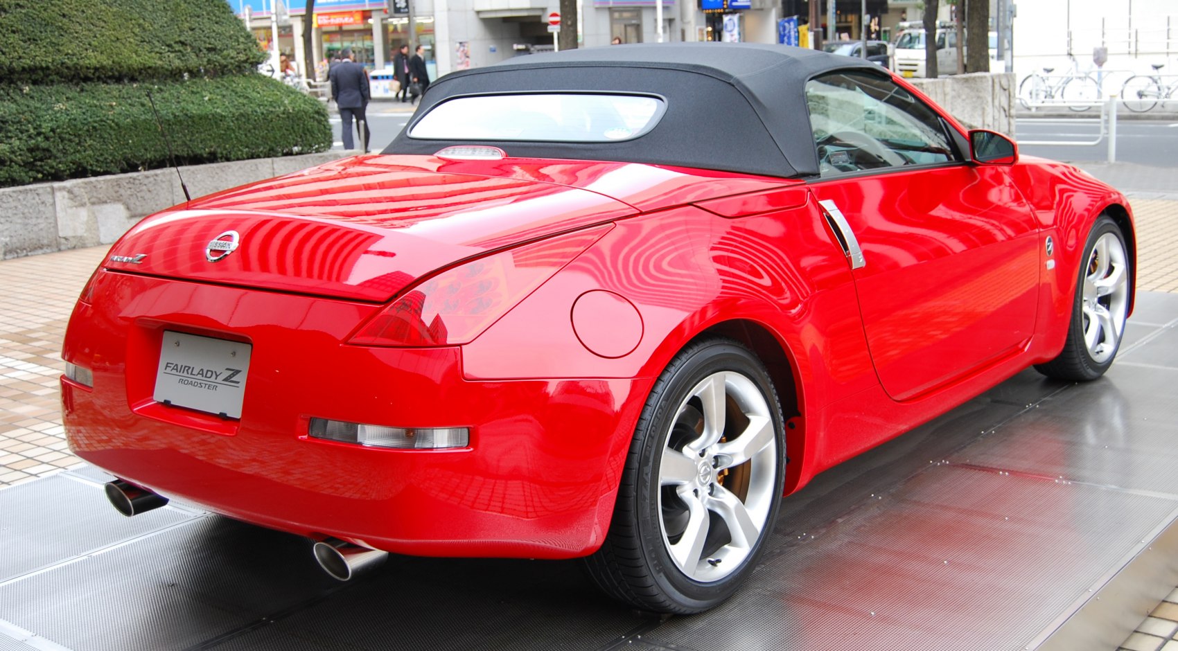 Rear and side view of red convertible with soft top, alloy wheels and dual exhaust