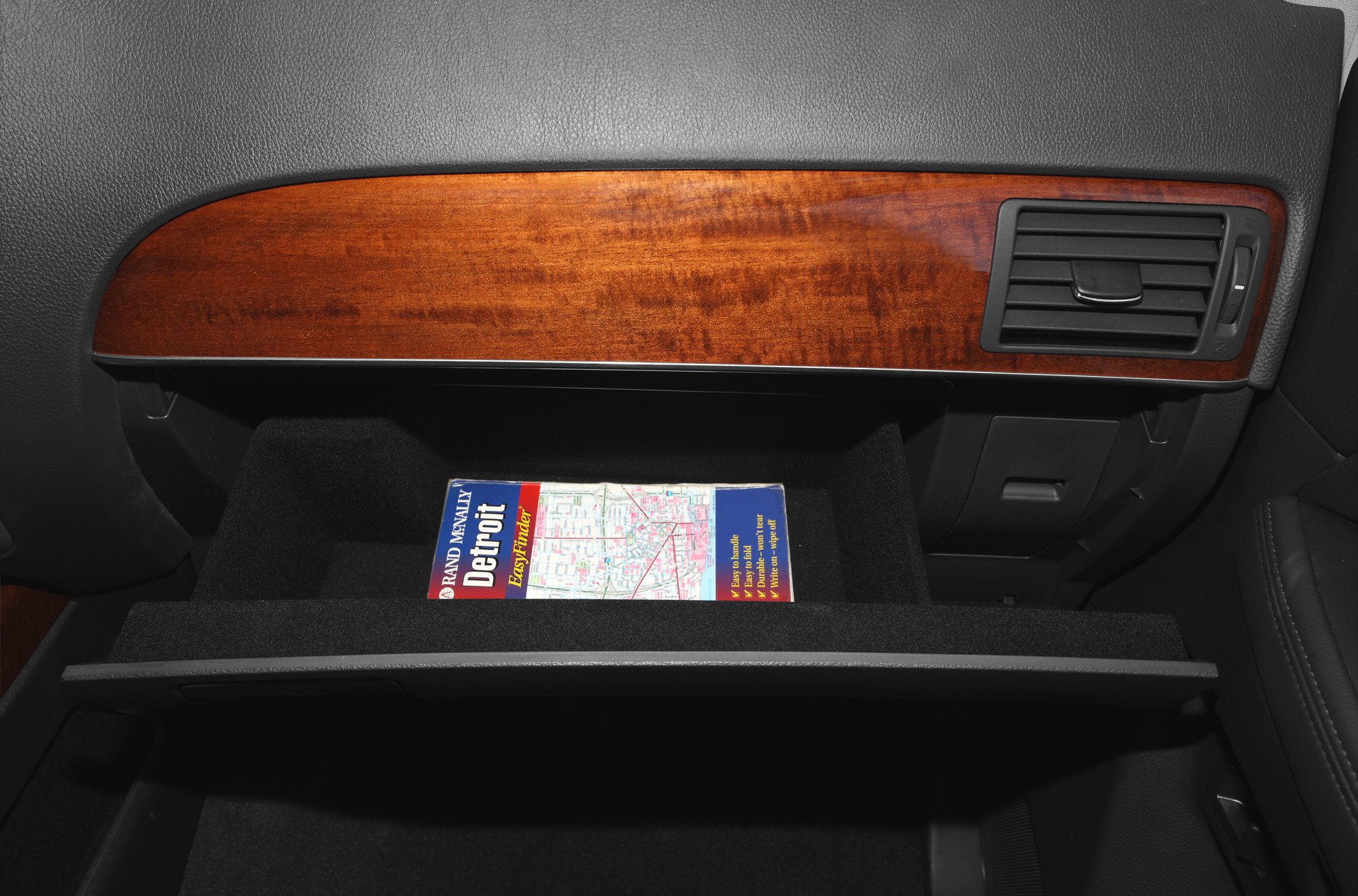 Wood trim dashboard panel and open glovebox with a city map