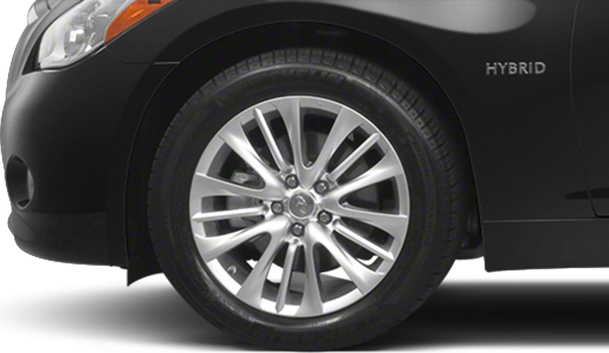 Close-up of hybrid badge and alloy wheel on black car.