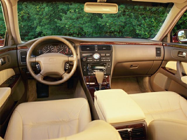 Dashboard, steering wheel, and center console with beige leather and wood trim