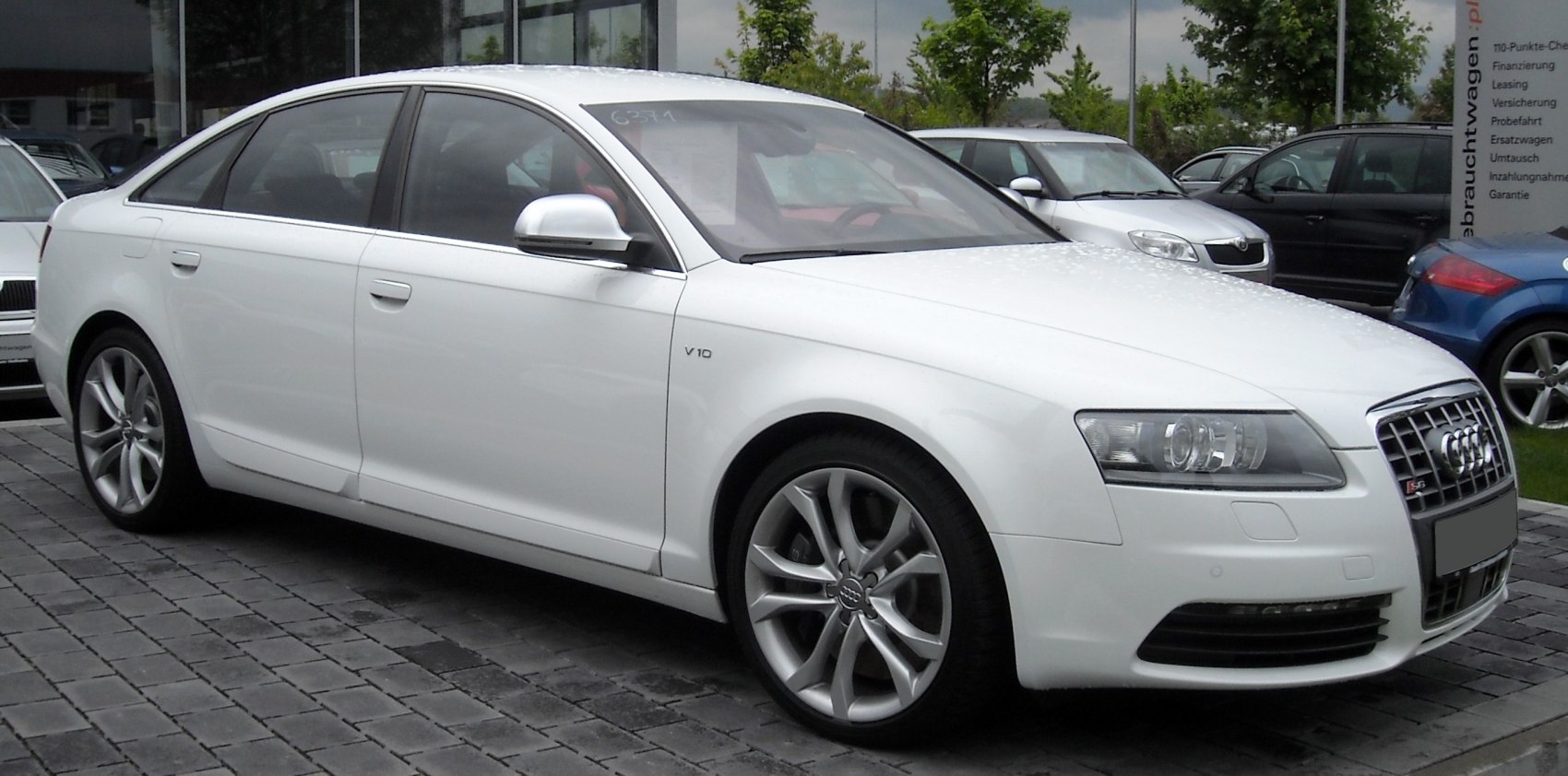 White luxury sedan with V10 badge and alloy wheels