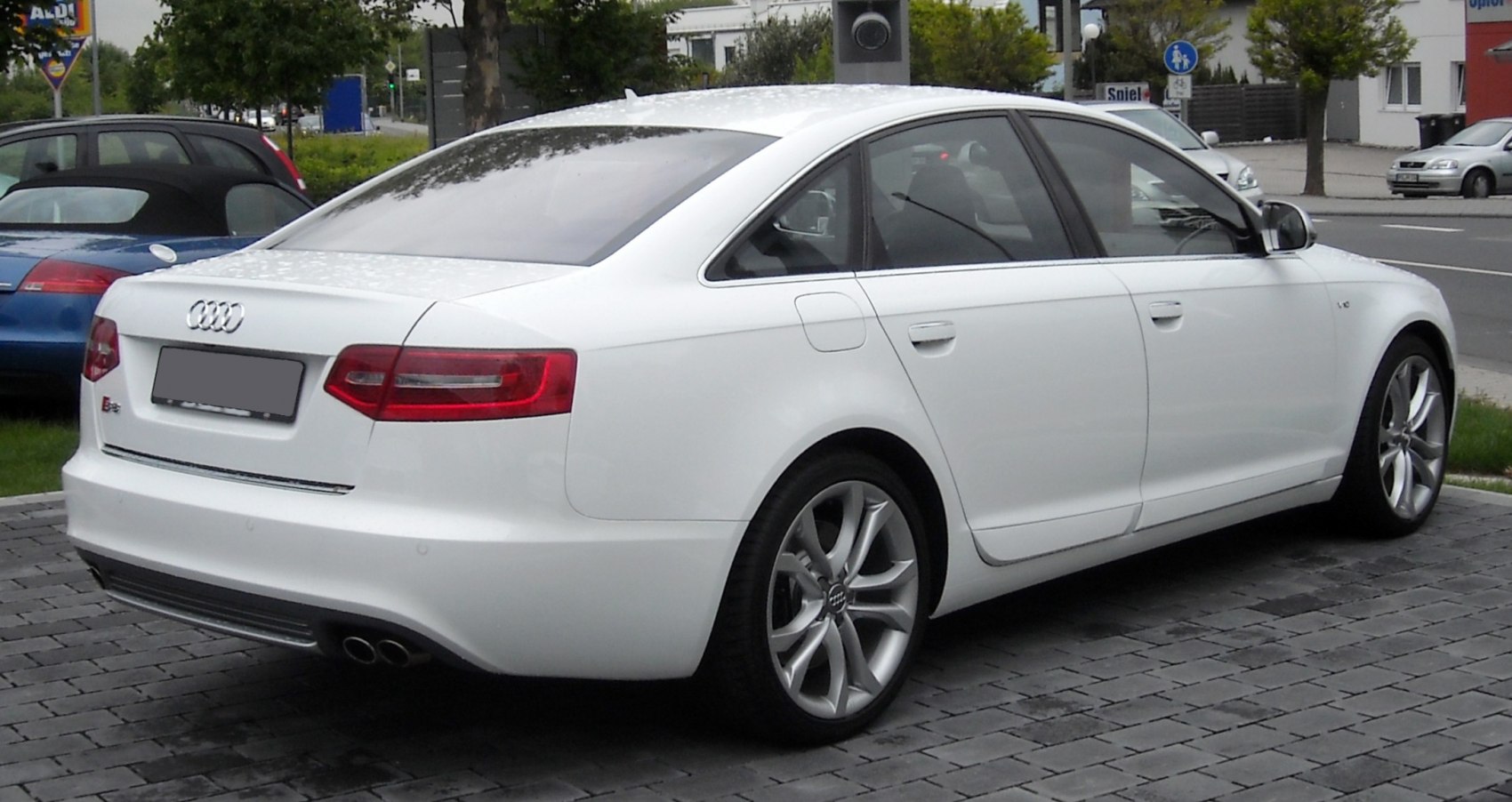 Rear side view of a white sedan with distinct taillights and dual exhaust
