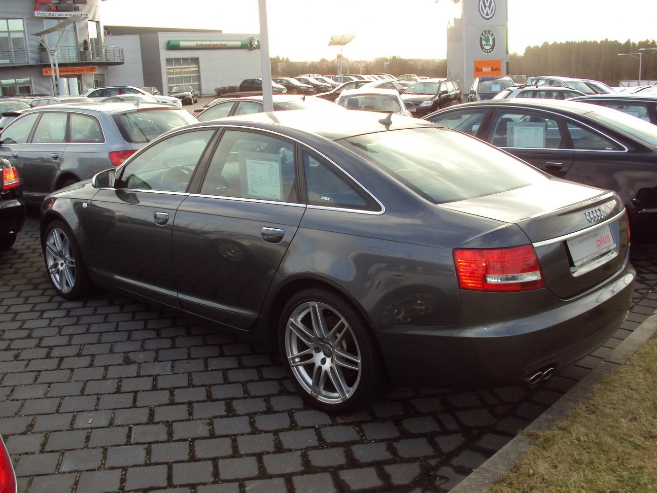 Rear side view of a metallic gray sedan with alloy wheels and dual exhaust